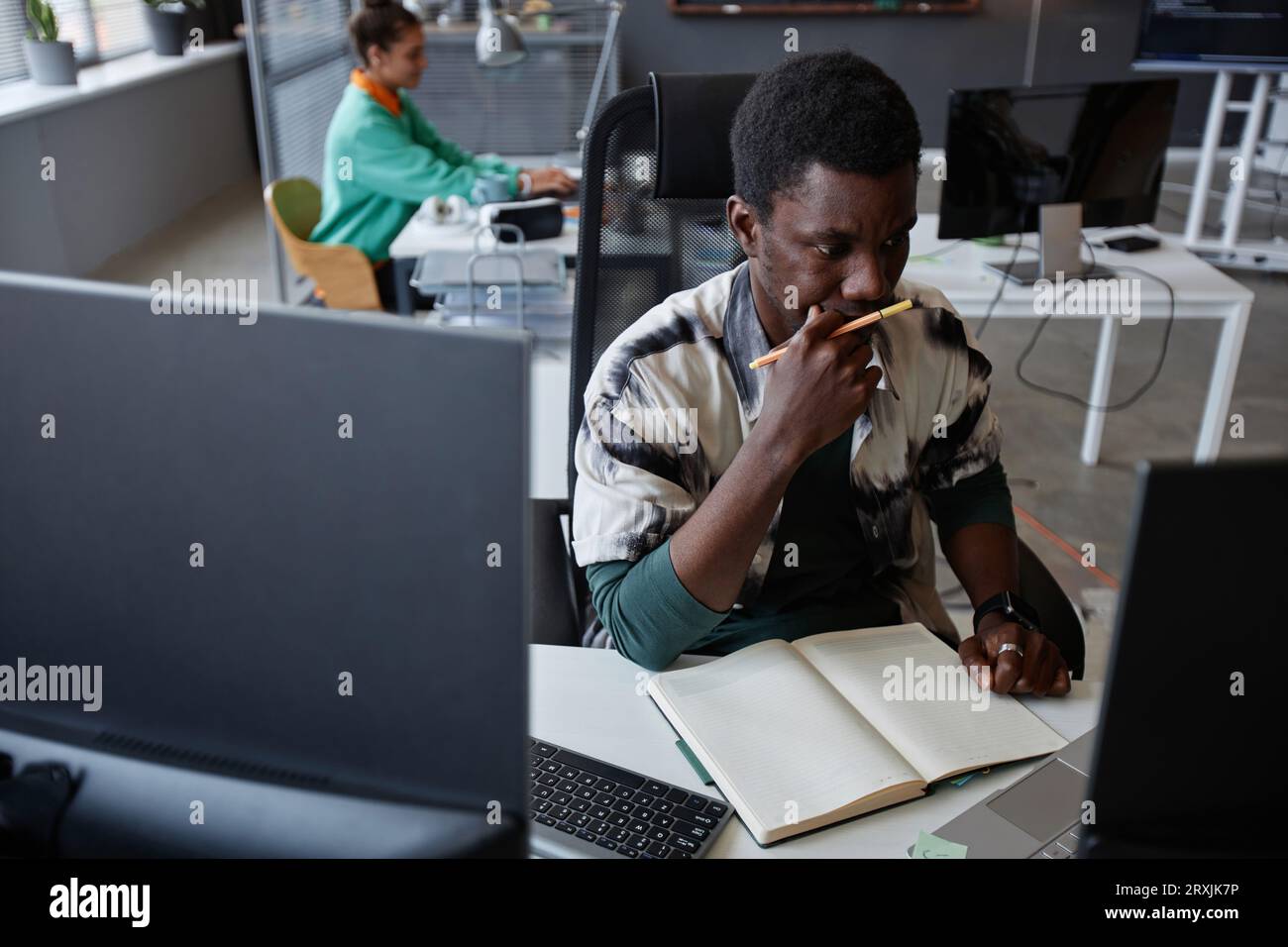 Pensive professional programmer developing new project while sitting at his workplace Stock Photo