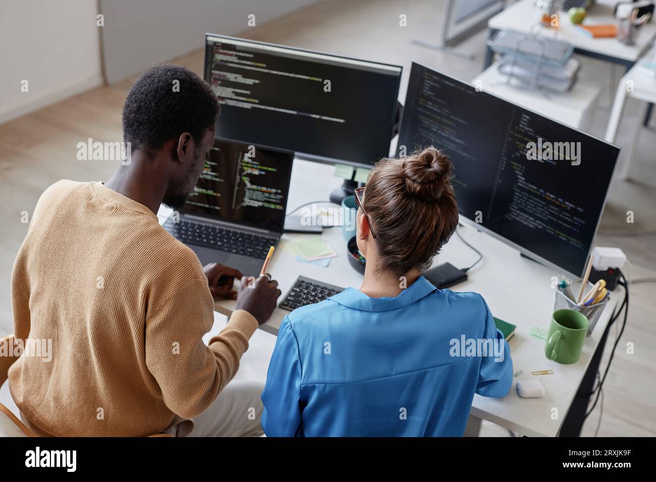 High angle view of colleagues developing security codes on computer in team during their work in IT office Stock Photo
