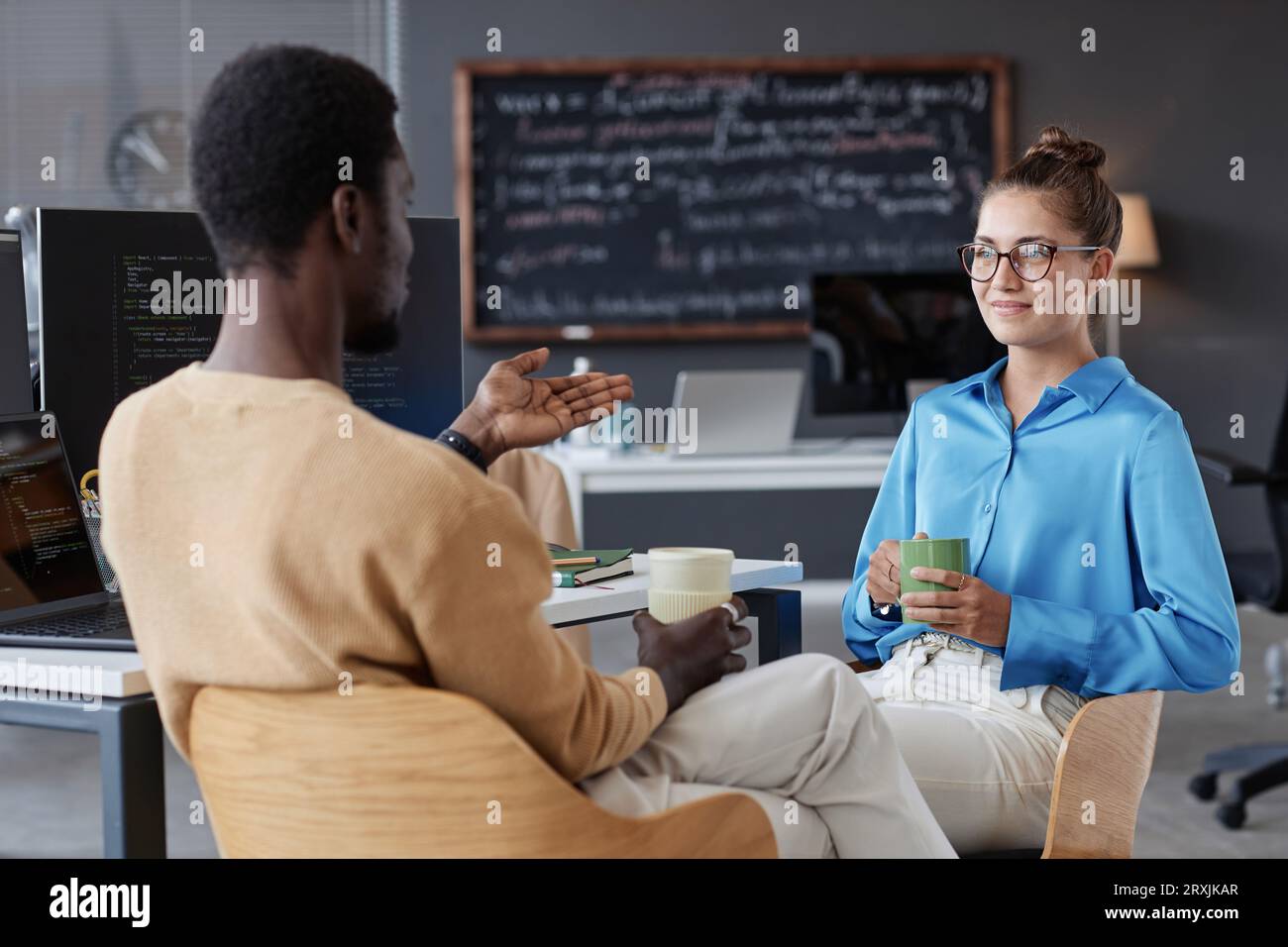 Young programmers discussing new software while drinking coffee in office Stock Photo