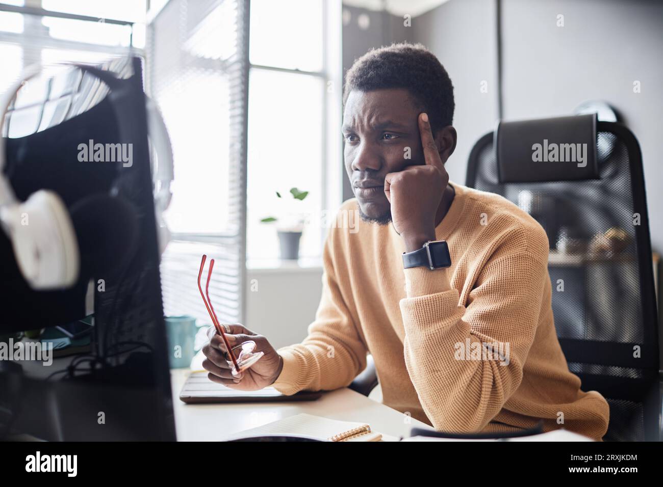 Pensive programmer thinking about development of new software during his work at table in IT office Stock Photo