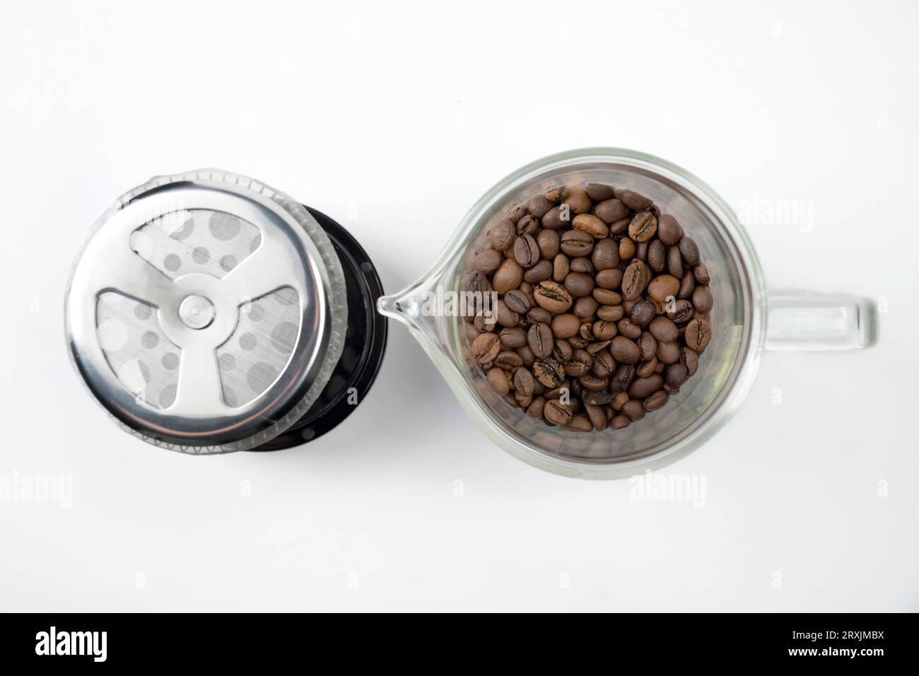 Coffee beans in a French press coffee maker isolated over a white