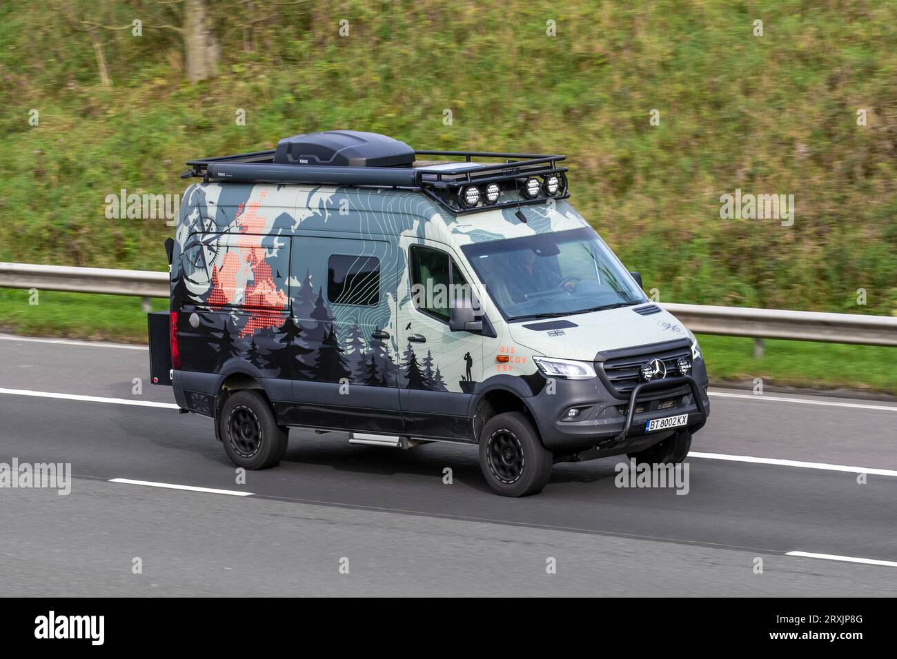 Custom Mercedes Benz Adventure Leisure motorhomes, with decals, stickers and vehicle wrapping on Mercedes-Benz Sprinter, 2500 Winnebago Revel 4×4, two-people off-roader van chassis; travelling at speed on the M6 motorway in Greater Manchester, UK Stock Photo