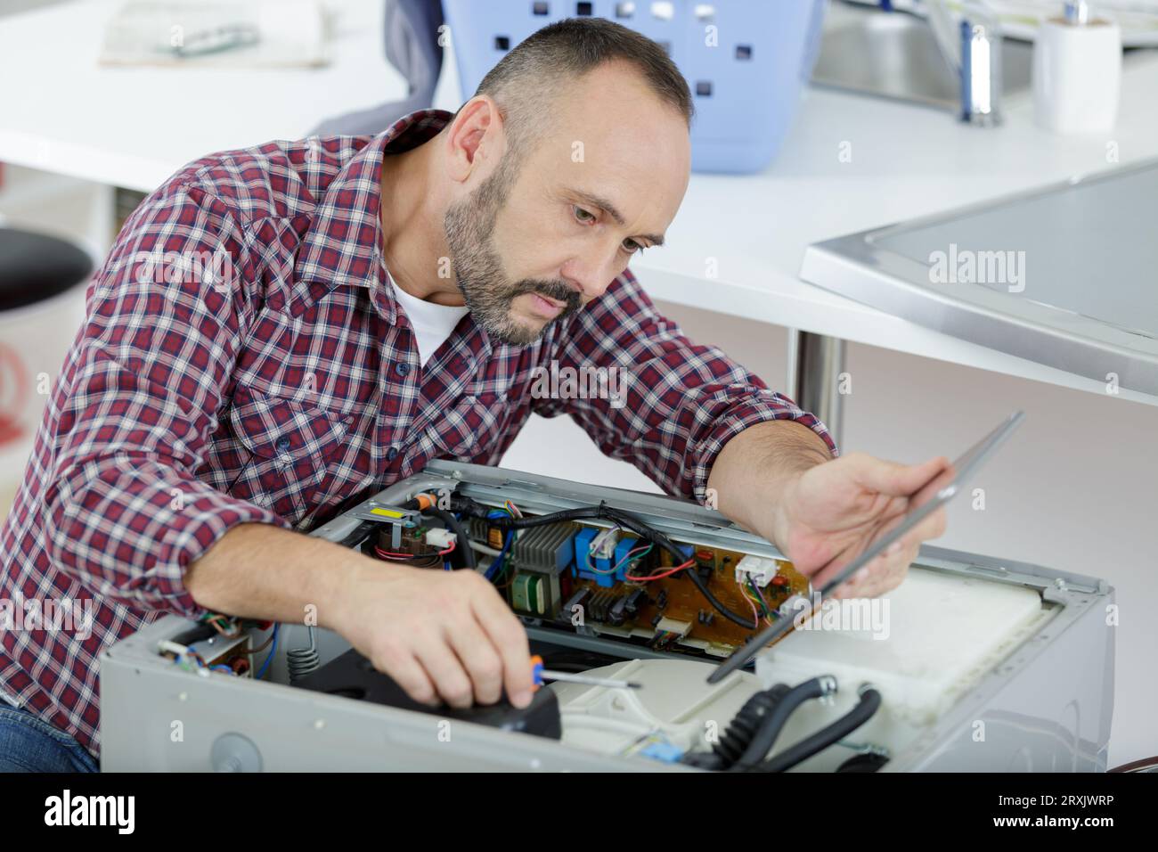 serviceman looking at tablet while repairing washing machine Stock Photo