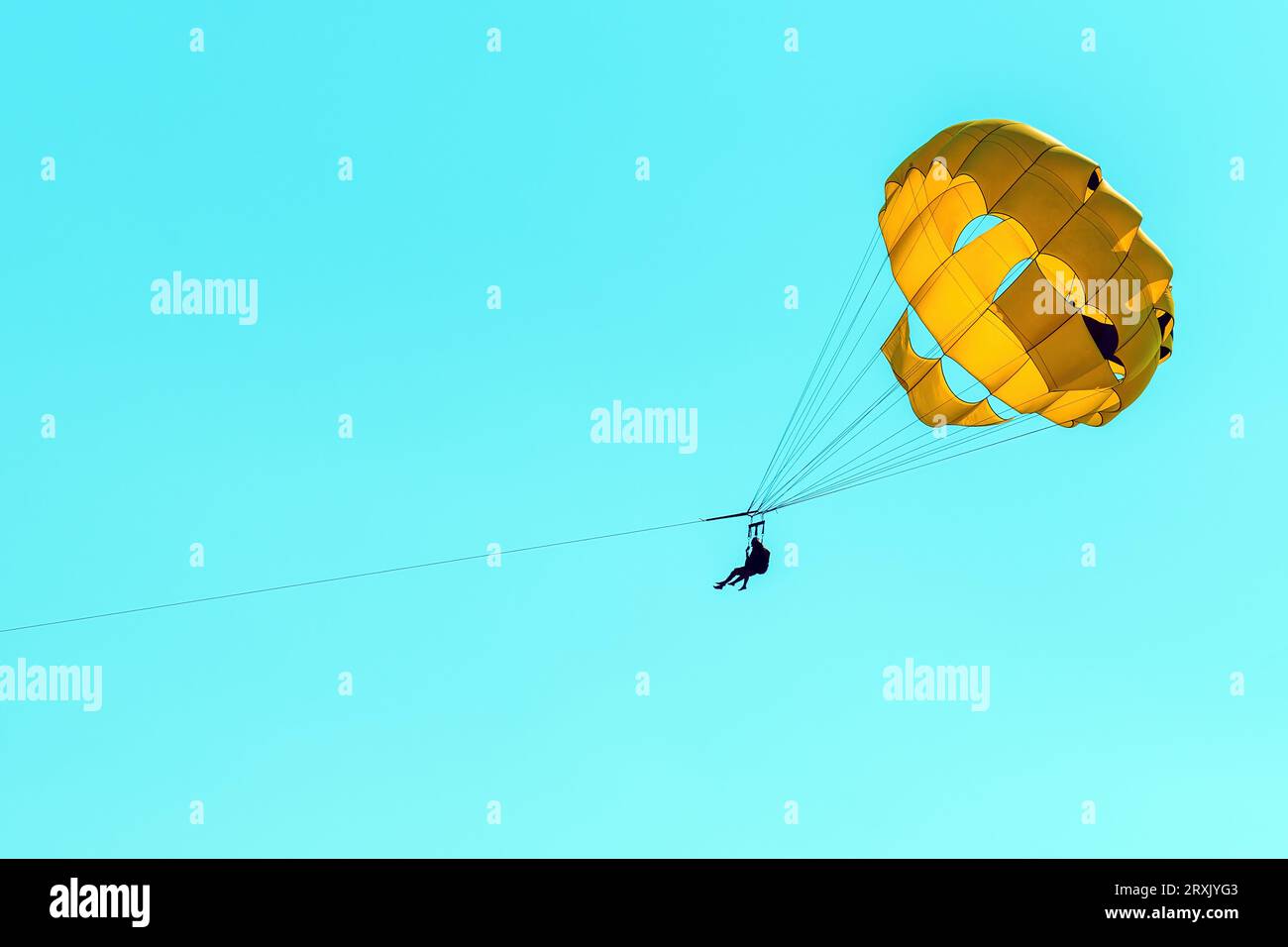 Parasailing, female person with instructor using parachute, against blue summer sky Stock Photo