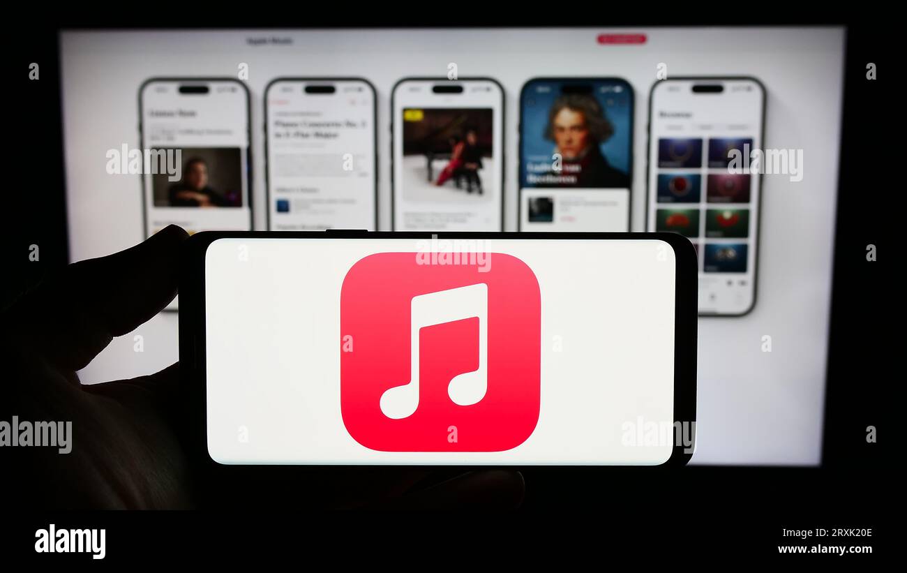Person holding smartphone with logo of streaming service platform Apple Music on screen in front of website. Focus on phone display. Stock Photo