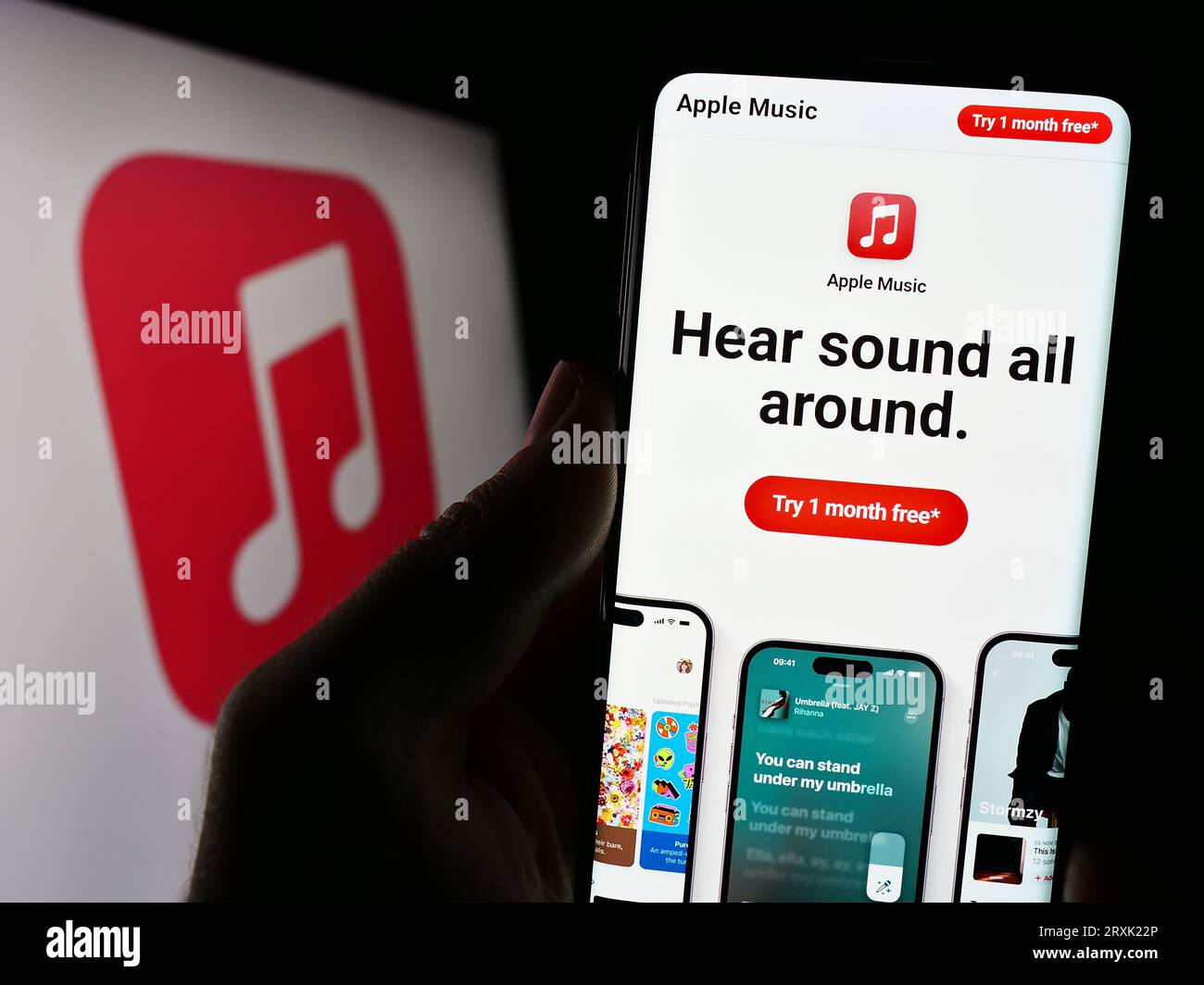Person holding cellphone with webpage of streaming service platform Apple Music on screen in front of logo. Focus on center of phone display. Stock Photo