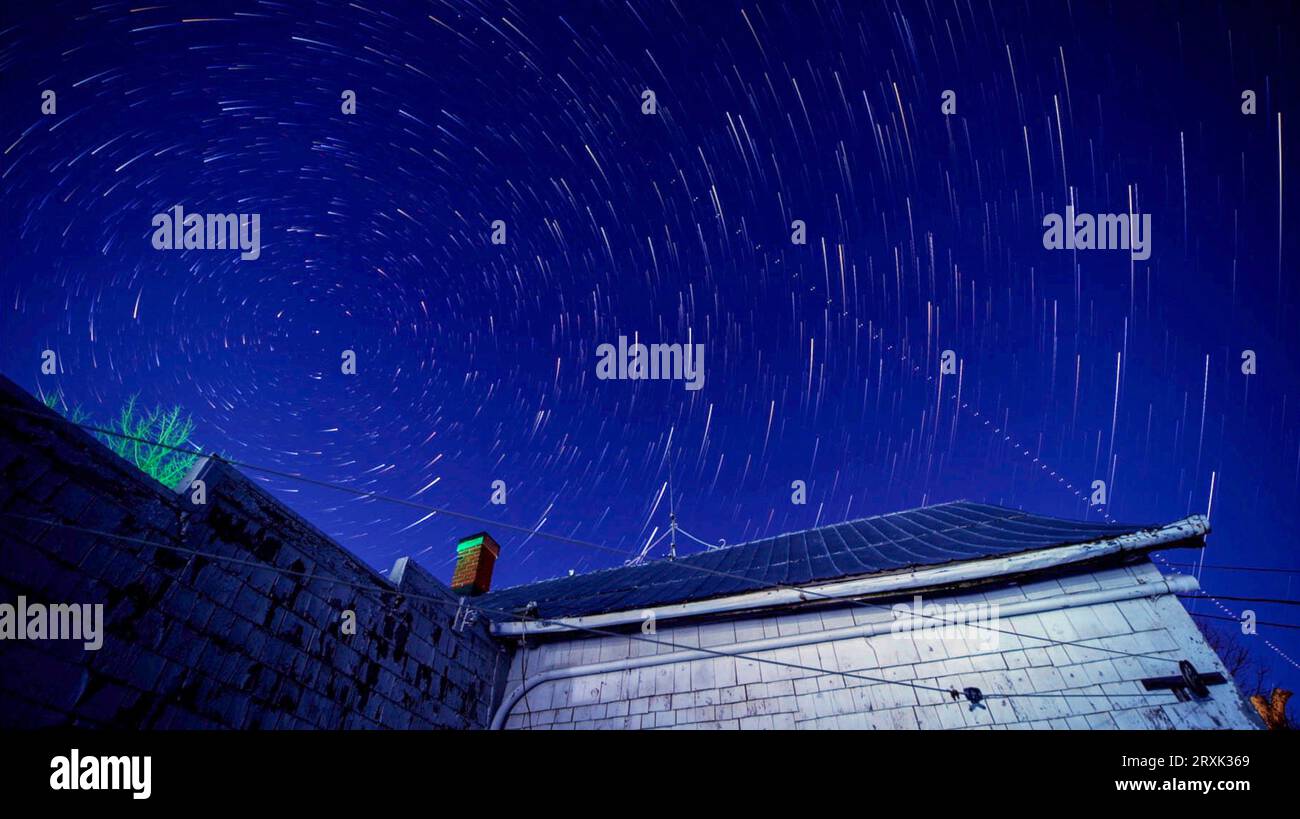 Star trails over old house Stock Photo