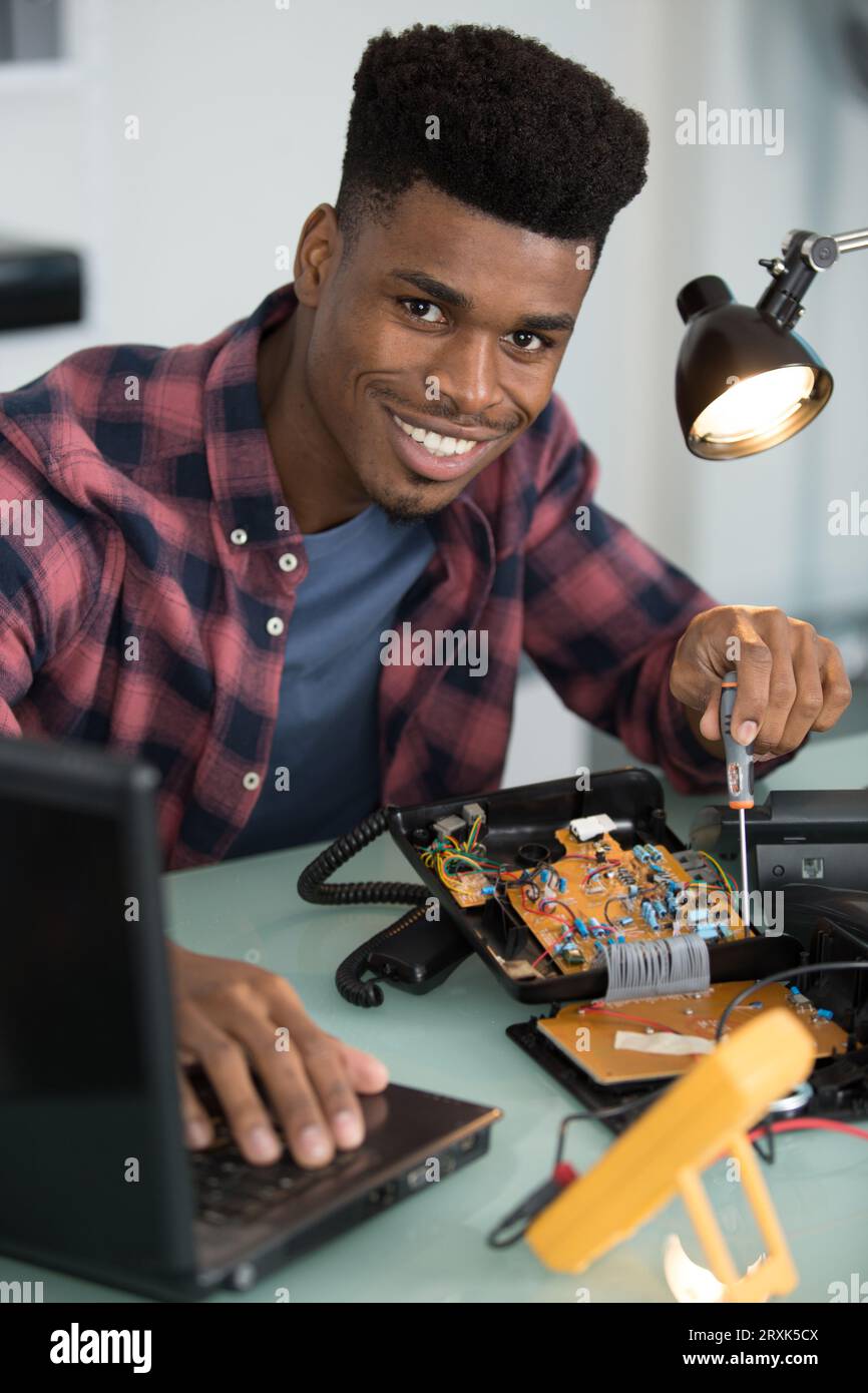 smiling man using multimeter while fixing pc Stock Photo