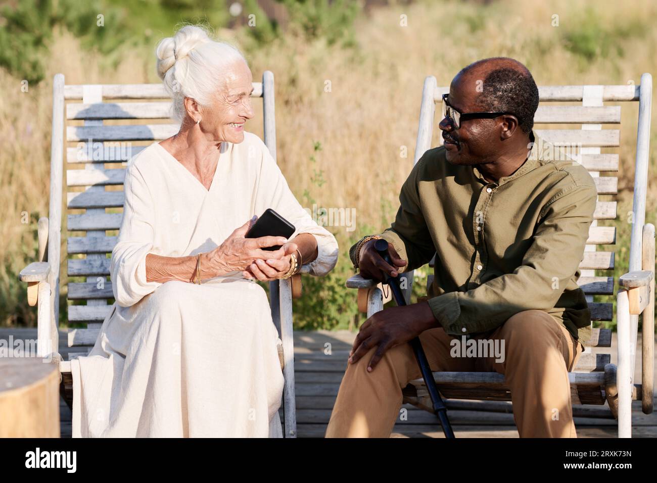 Senior couple sitting on chairs outdoors and enjoying their conversation Stock Photo