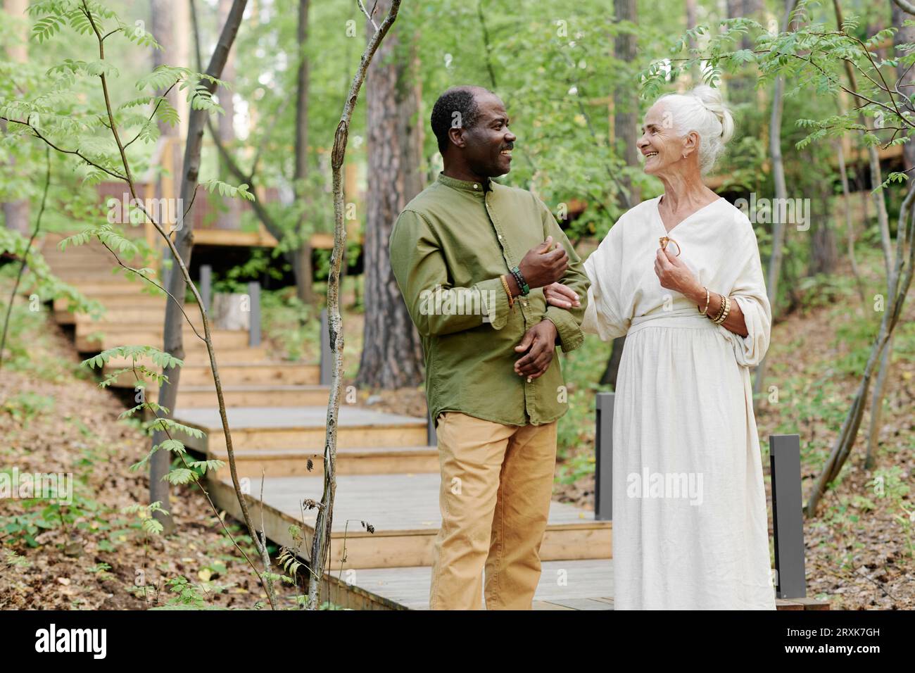 Senior couple enjoying their walk outdoors, they standing in the forest and talking to each other Stock Photo