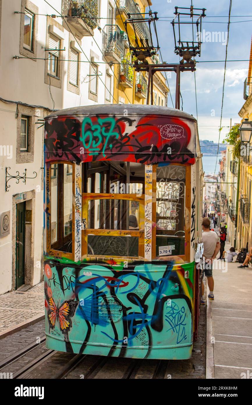 Famous hill tram with graffiti in Lisbon, Portugal. Electric elevator train in Lisboa. Portuguese traditional transport. Lisbon street. Stock Photo