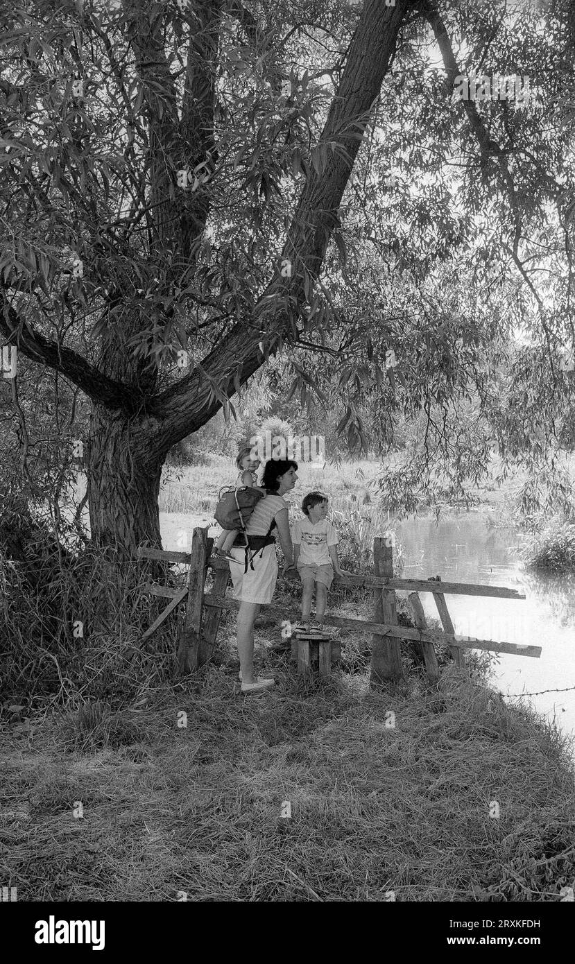 A mother with her two children taking a riverside walk by the Windrush ...