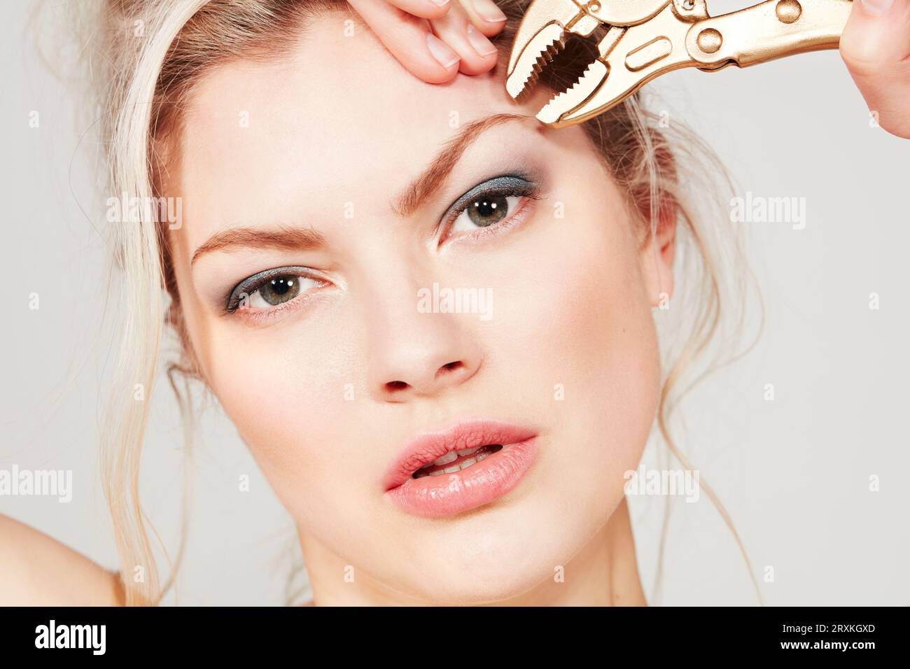 Young woman using pliers on her eyebrow Stock Photo
