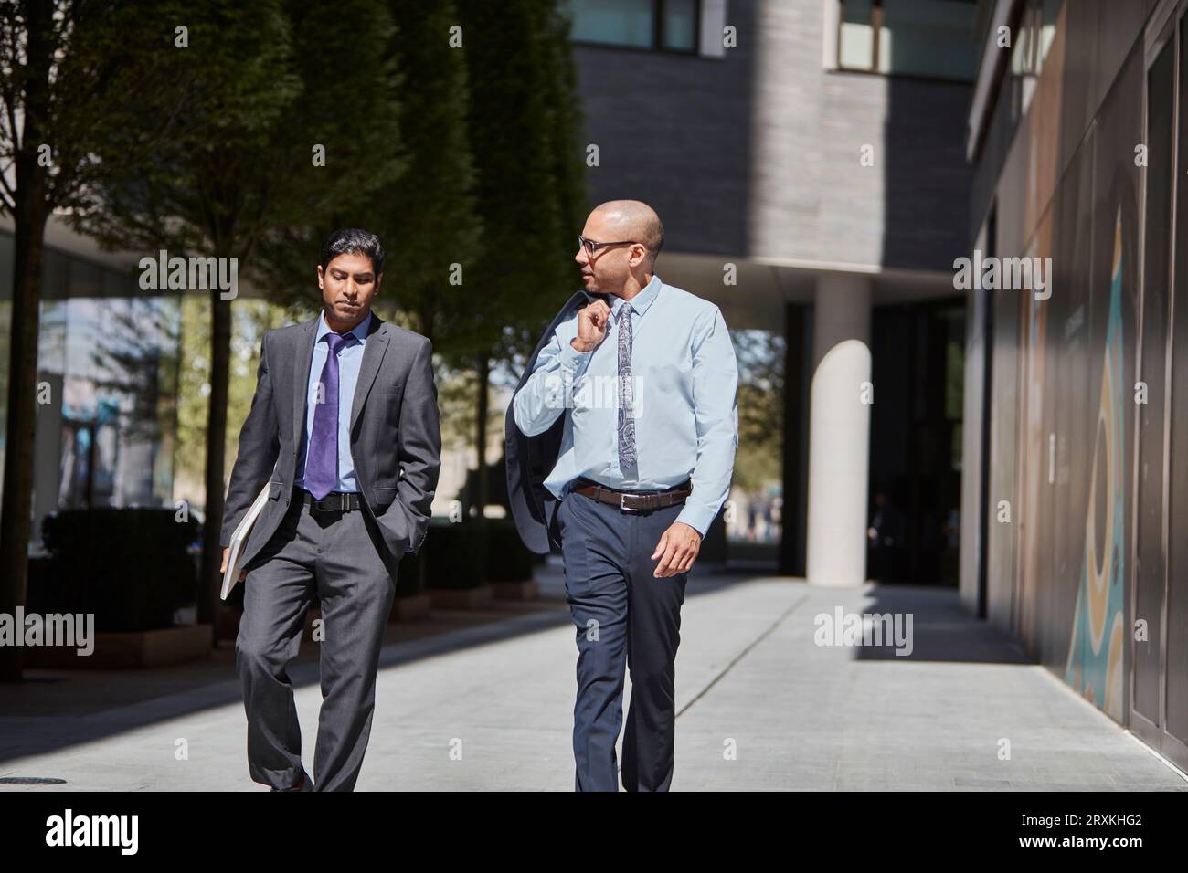 Businessmen walking along sidewalk together Stock Photo
