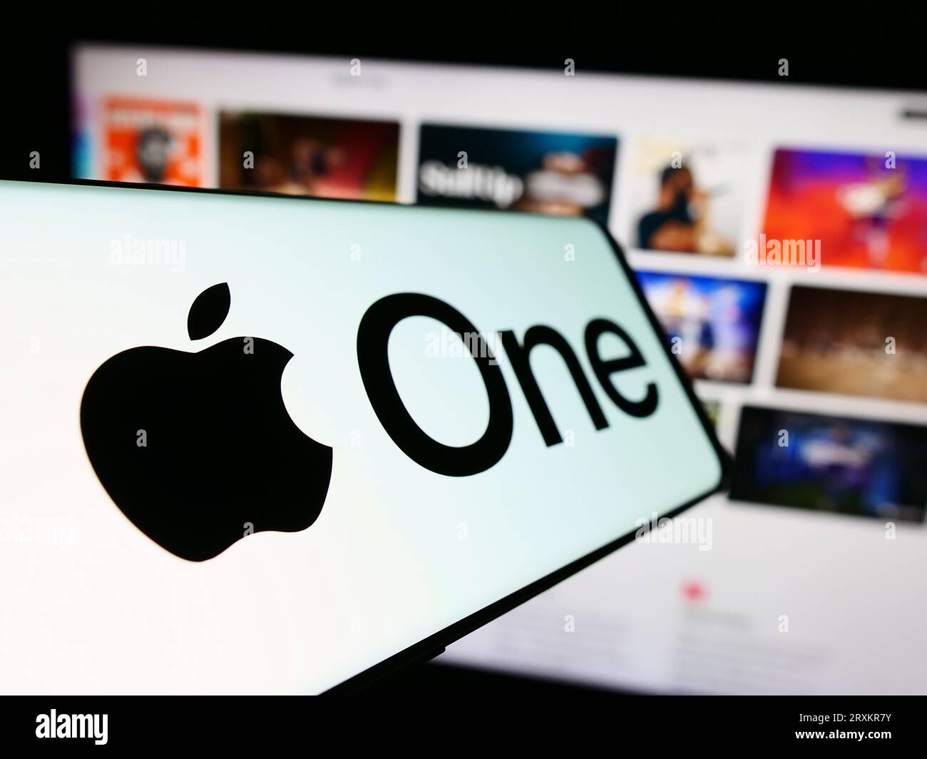 Cellphone with logo of subscription service Apple One on screen in front of business website. Focus on center-left of phone display. Stock Photo