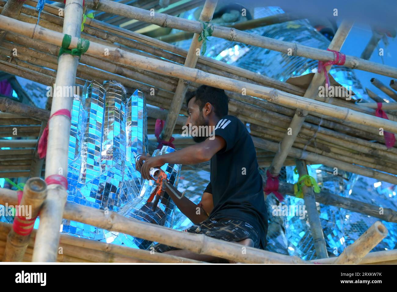 An artist is pasting glass pieces to make a 41 feet tall Ganesh idol, fully covered by glass, ahead of Ganesh Chaturthi festival in a pandal in Ranir bazar. Agartala. Tripura. India. Stock Photo