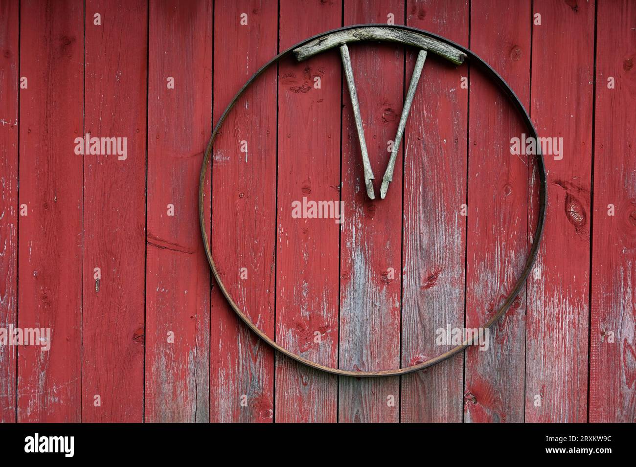 part of a wooden cart wheel on a red wooden wall of a traditional barn in Finland Stock Photo