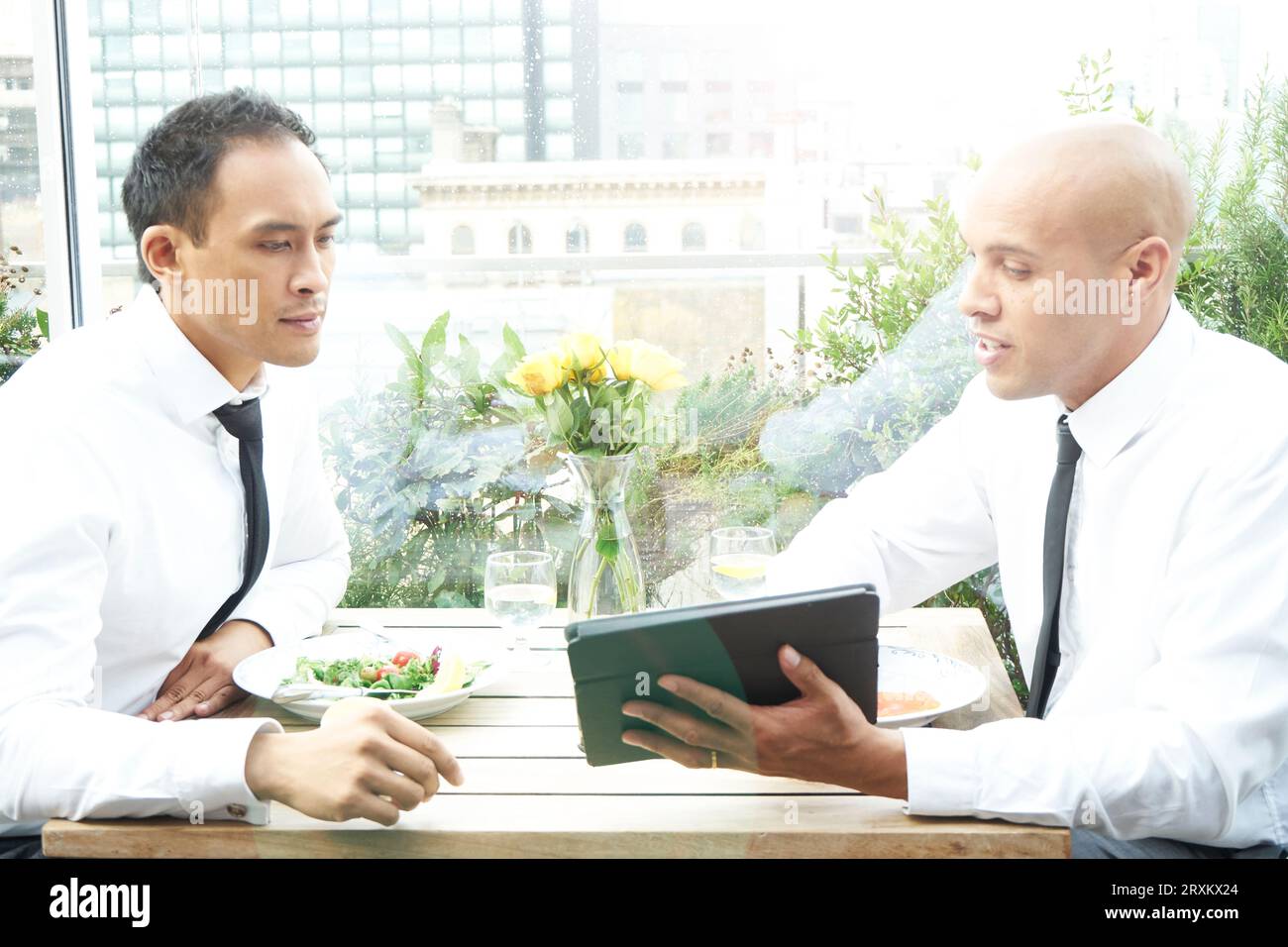 Businessmen using tablet PC during restaurant meeting Stock Photo