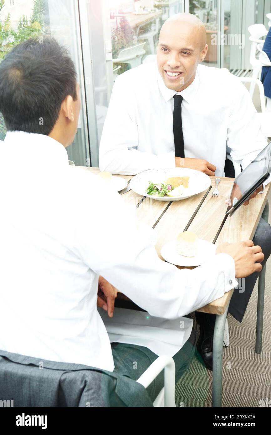 Businessmen using tablet PC during restaurant meeting Stock Photo