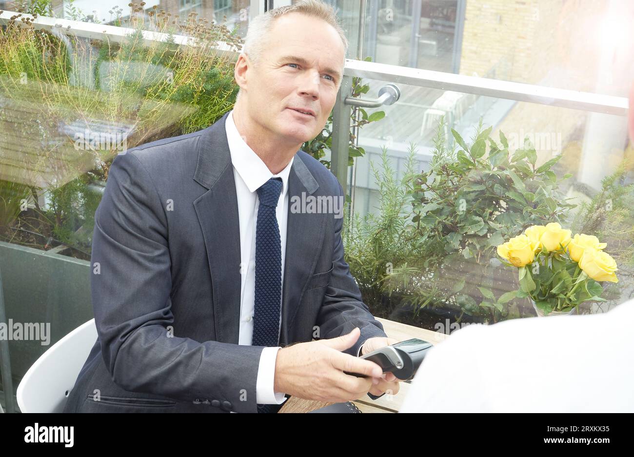Businessman using EFTPOS machine at restaurant table Stock Photo