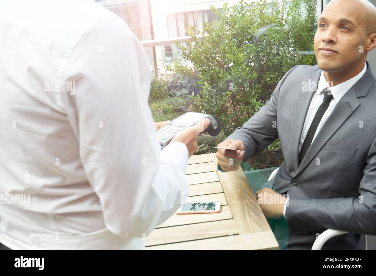 Businessman using EFTPOS machine at restaurant table Stock Photo