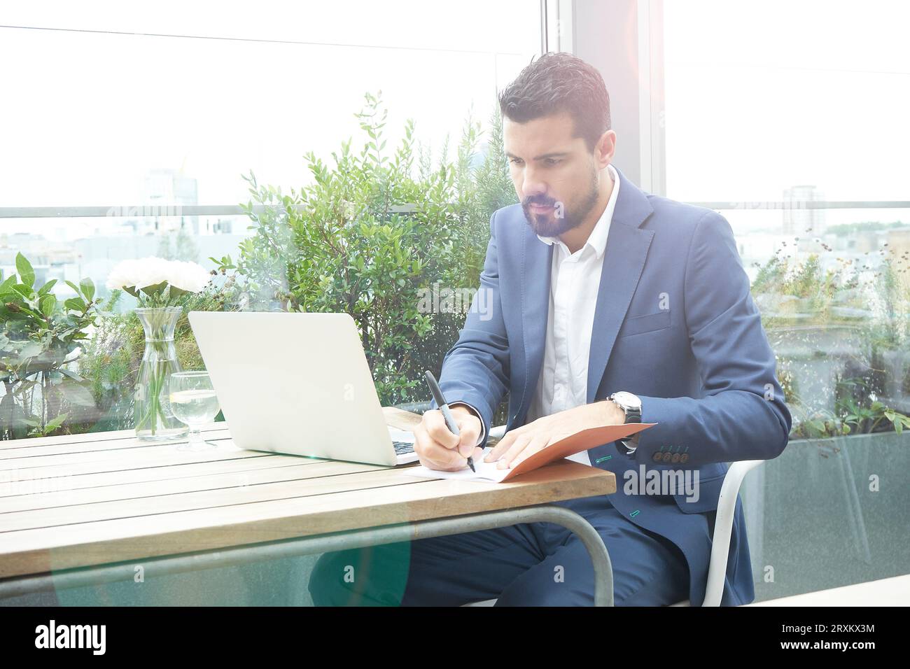 Businessman writing in notebook with laptop in restaurant Stock Photo