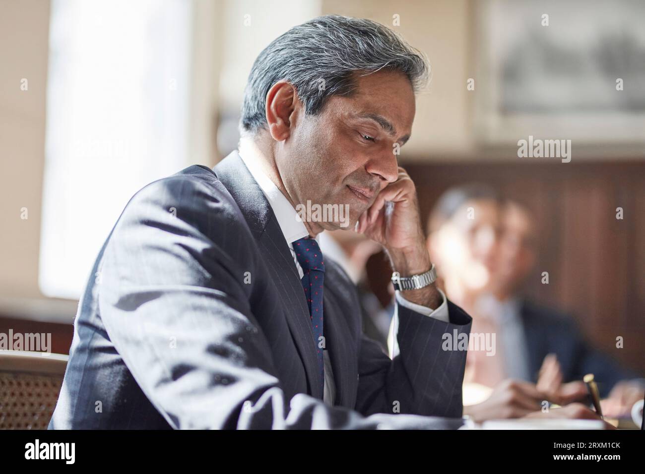 Businessman writing notes during meeting Stock Photo