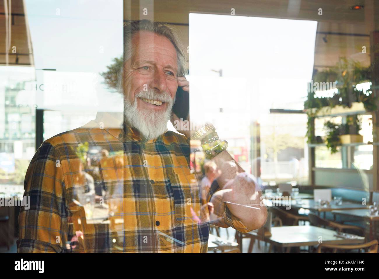 Senior man on phone call behind window Stock Photo