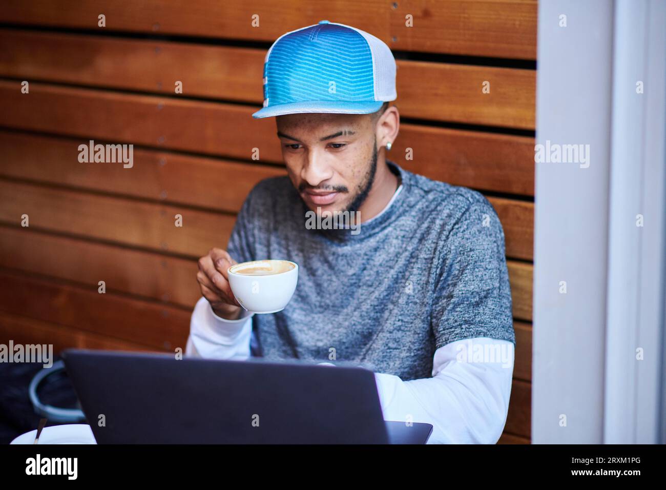 Young man with laptop drinking coffee Stock Photo