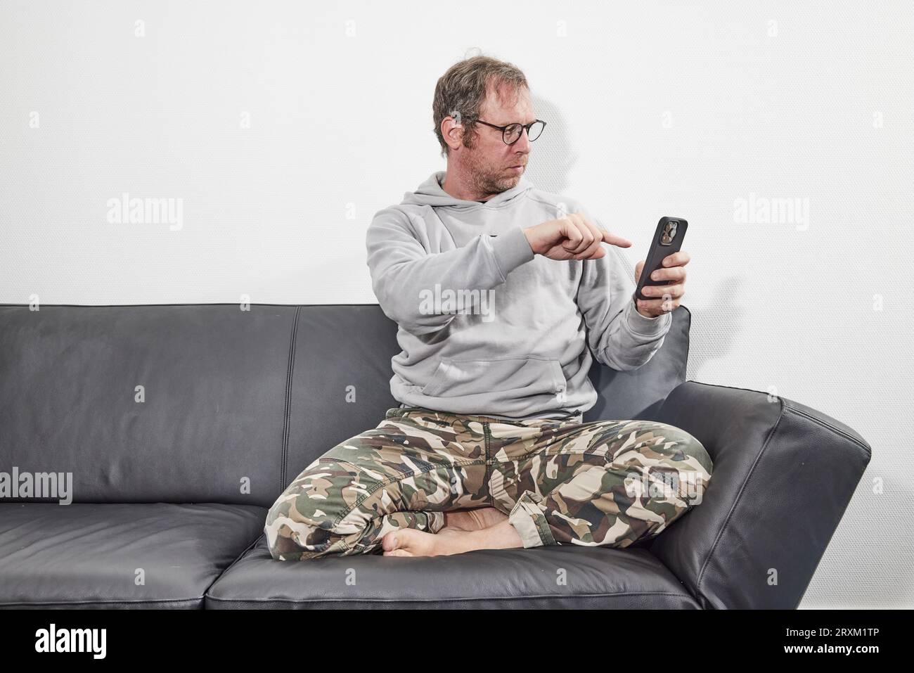 Man with glasses at home using mobile smart phone Stock Photo
