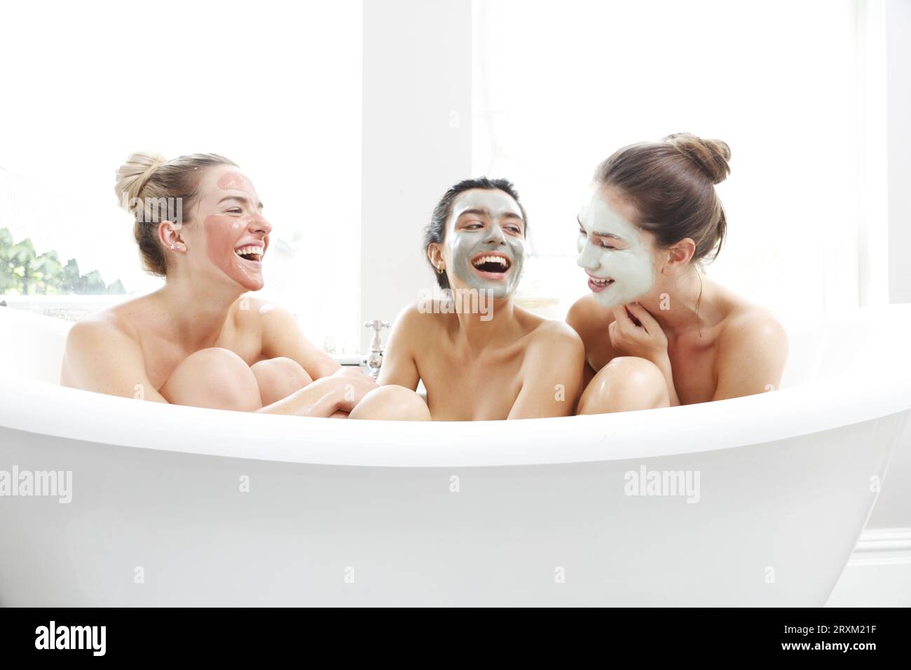 Friends enjoying a spa day with facial masks Stock Photo