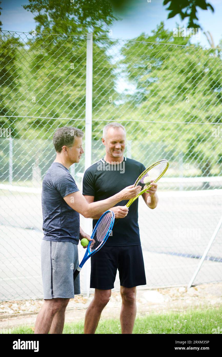 Gay couple holding tennis rackets and balls Stock Photo