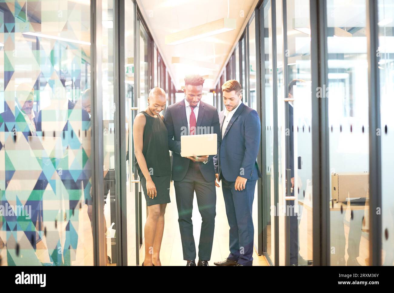 Businesspeople using laptop in office corridor Stock Photo