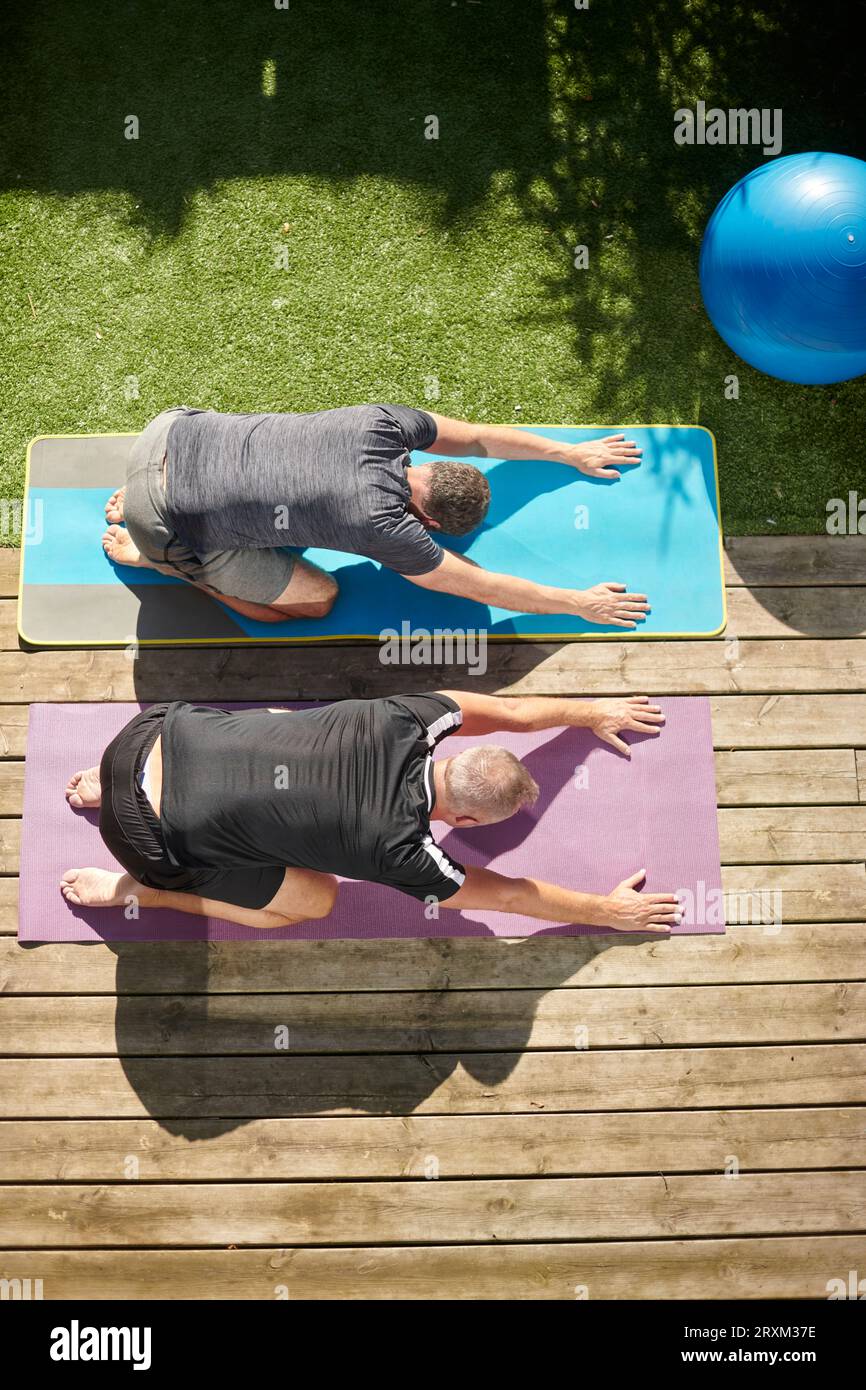 Mature couple practicing yoga in back yard Stock Photo
