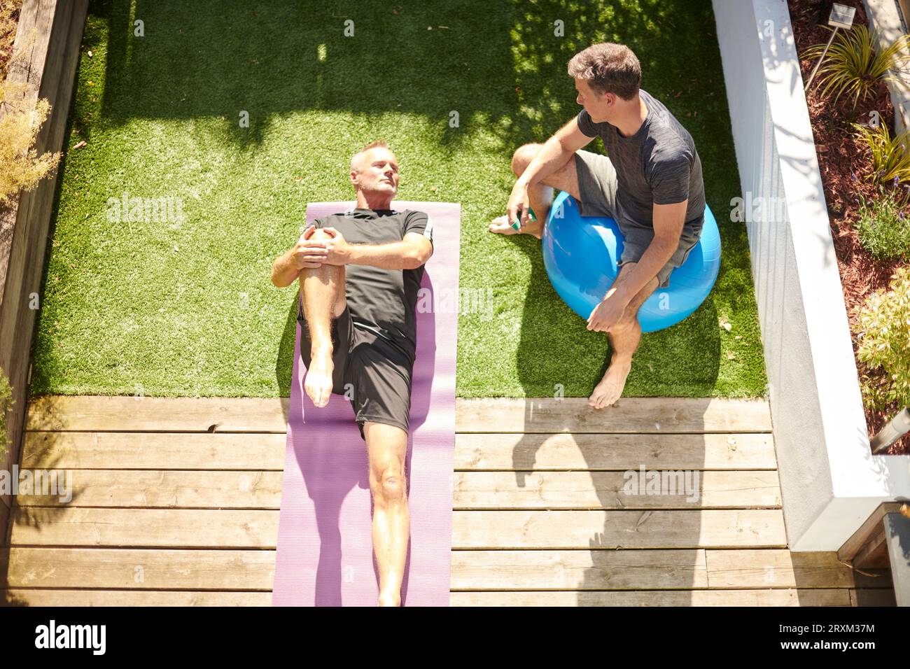 Mature couple practicing yoga in back yard Stock Photo