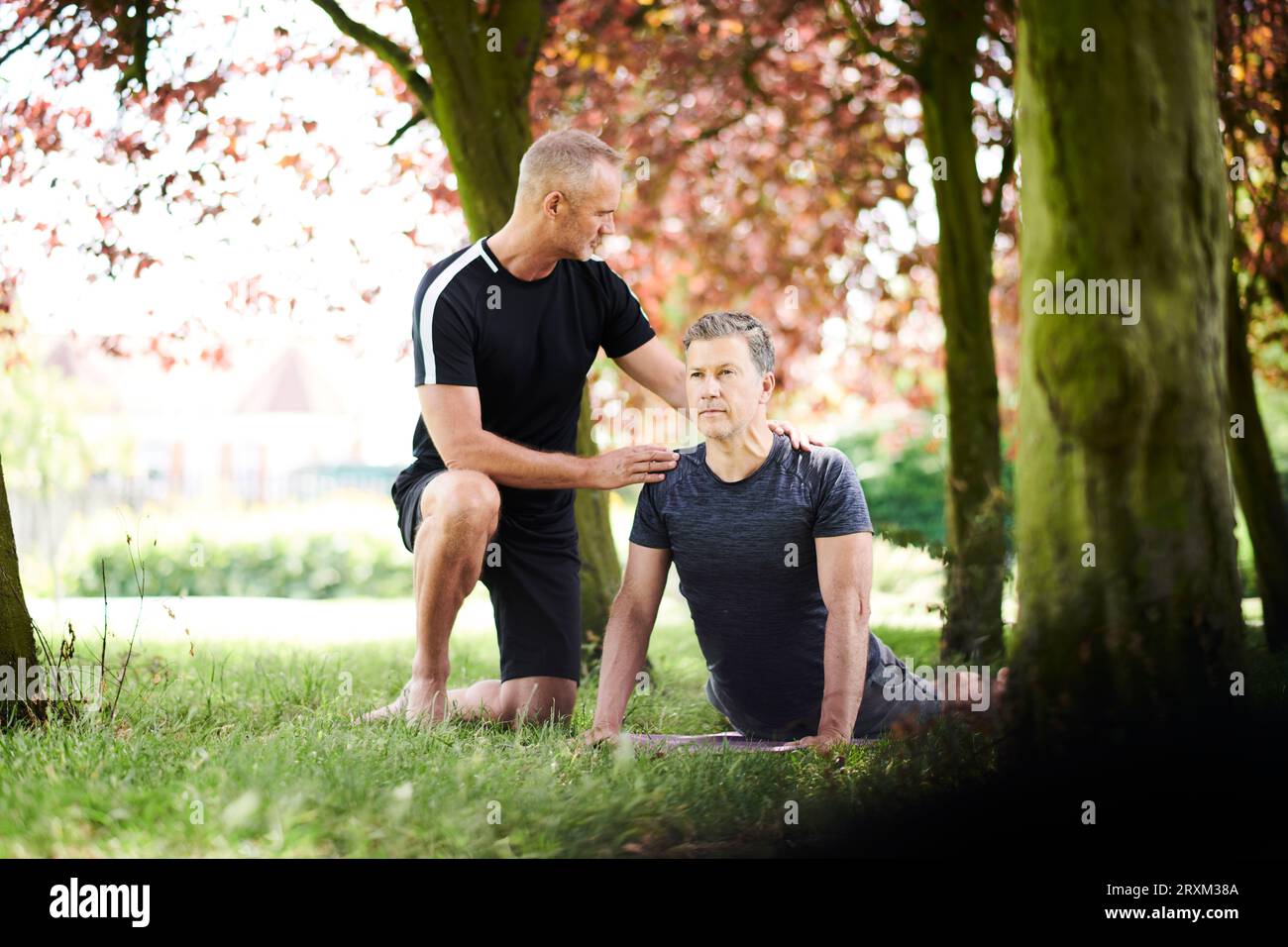 Mature men practicing yoga in park Stock Photo