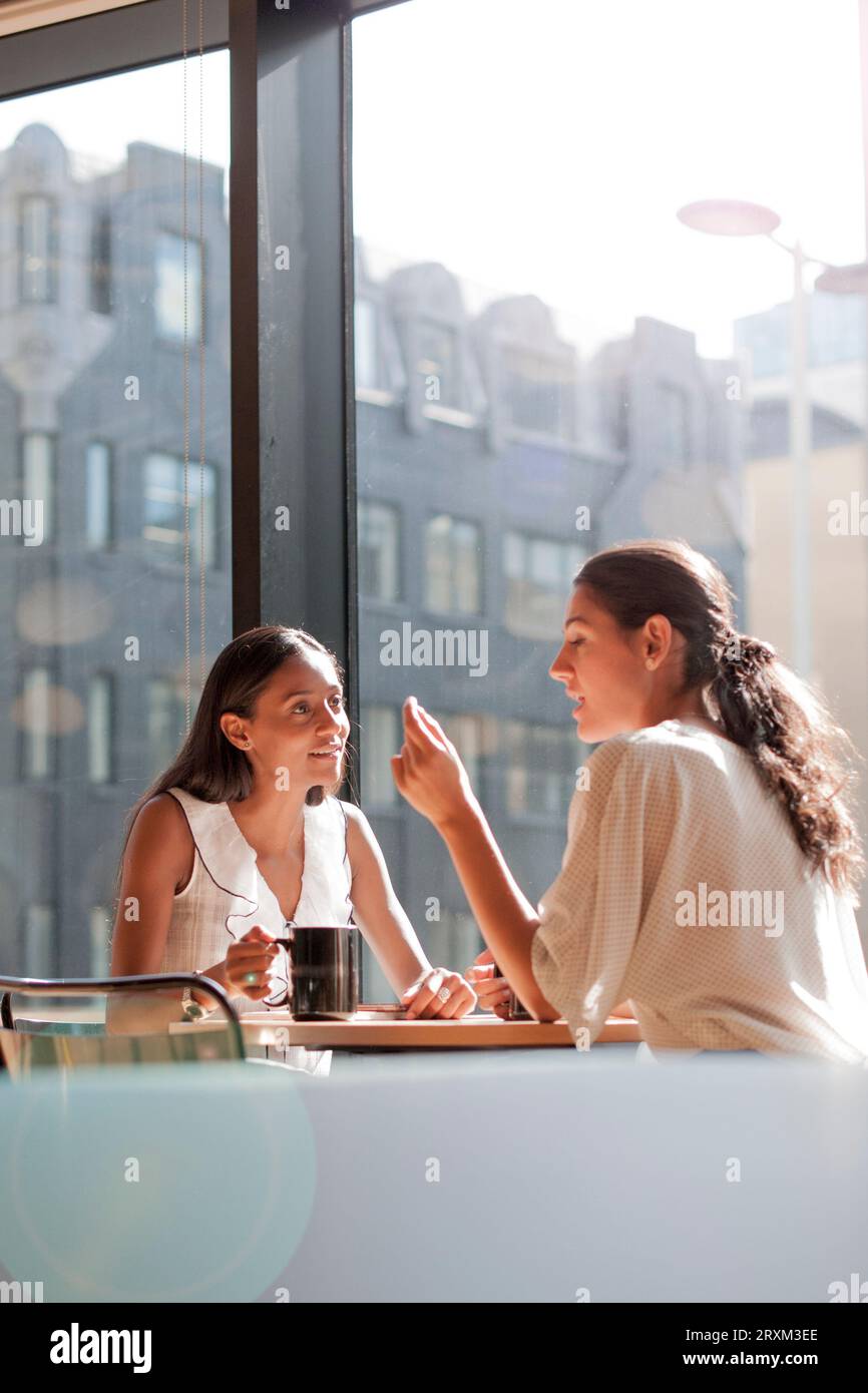 Businesswomen talking at table by window Stock Photo Alamy