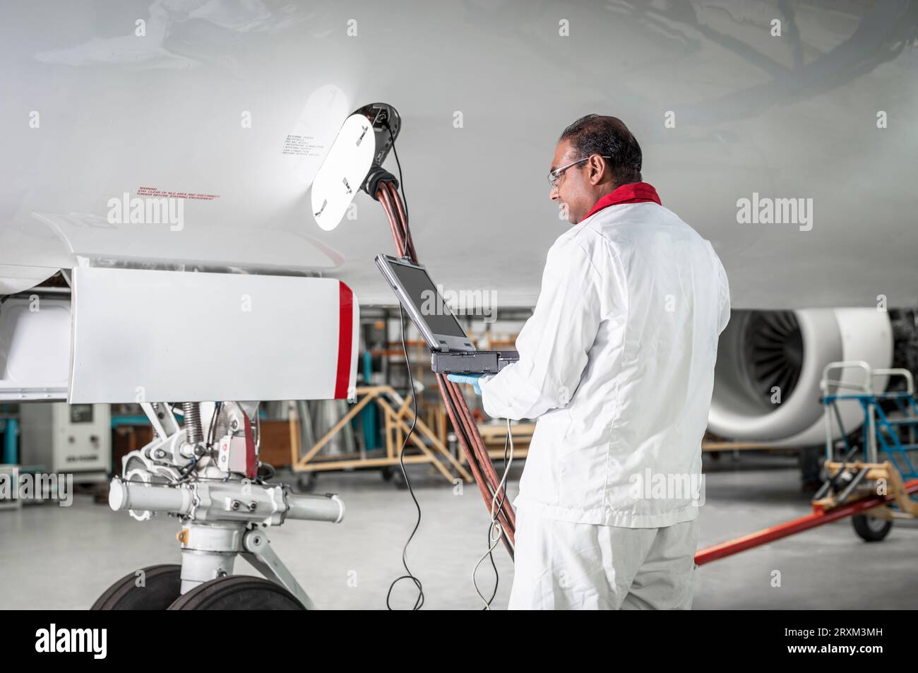 Man using laptop by airplane in hangar Stock Photo