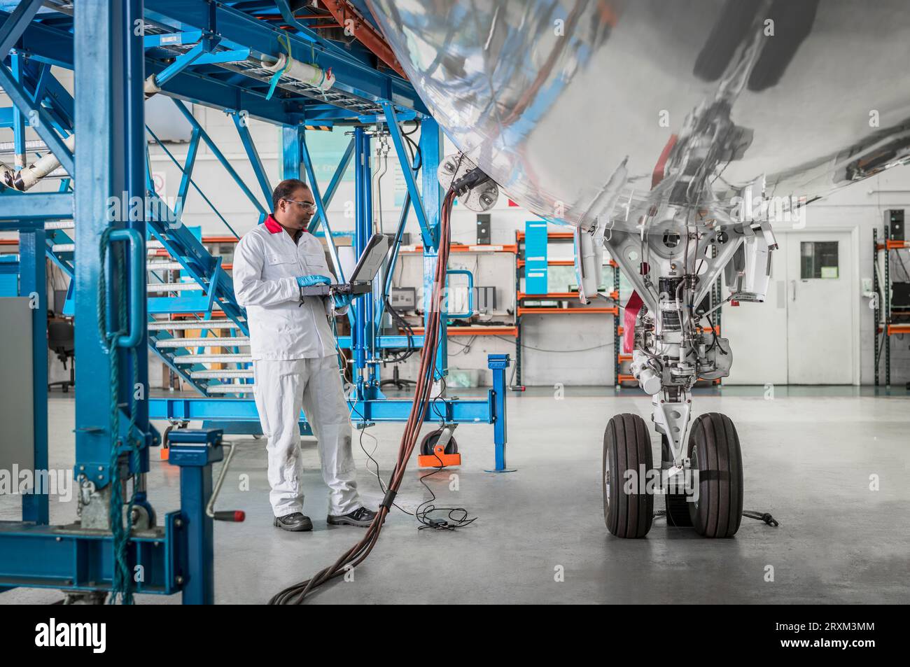 Man using laptop by airplane in hangar Stock Photo
