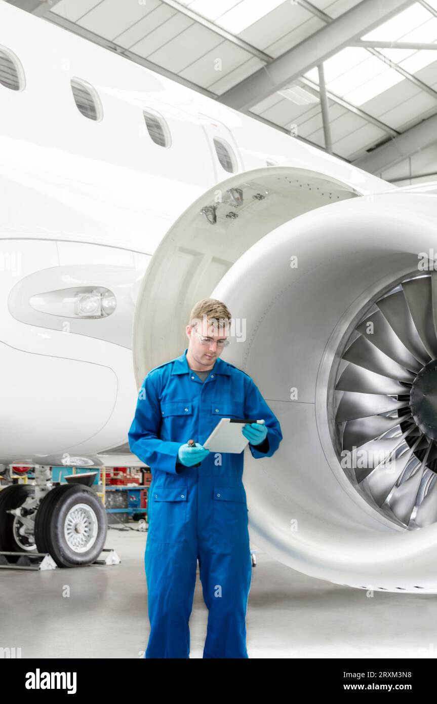 Young man using digital tablet by airplane engine Stock Photo