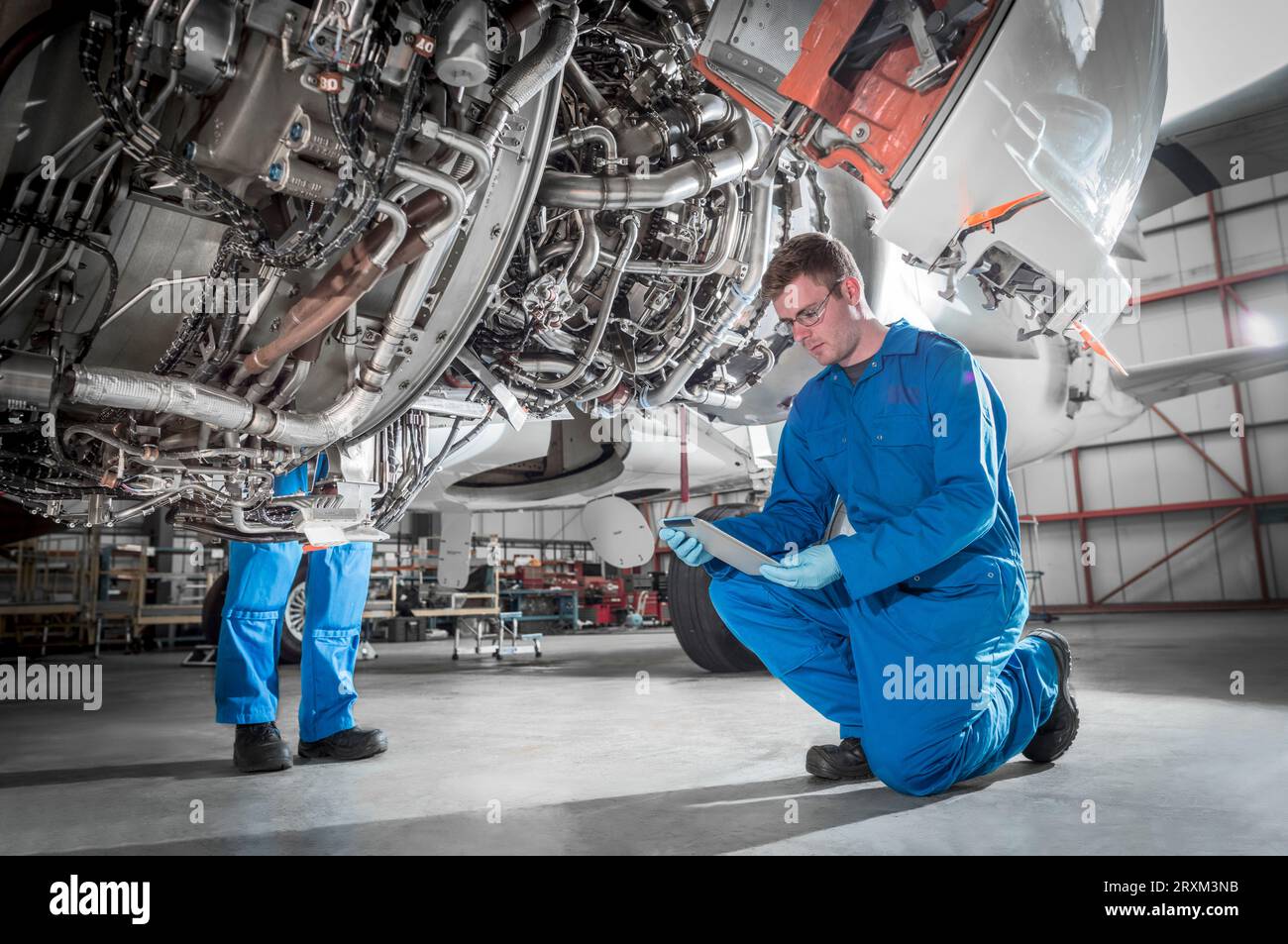 Crouched man using digital table by airplane Stock Photo