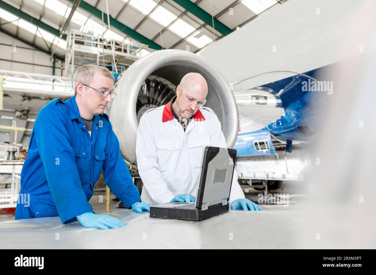 Men using laptop by airplane in hangar Stock Photo