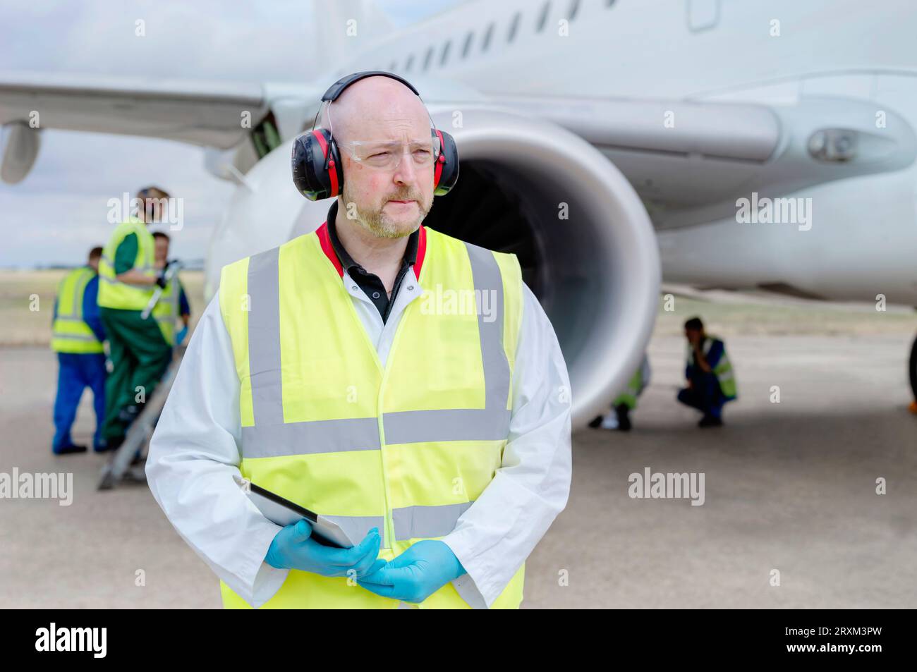 Middle aged man holding digital tablet by airplane Stock Photo