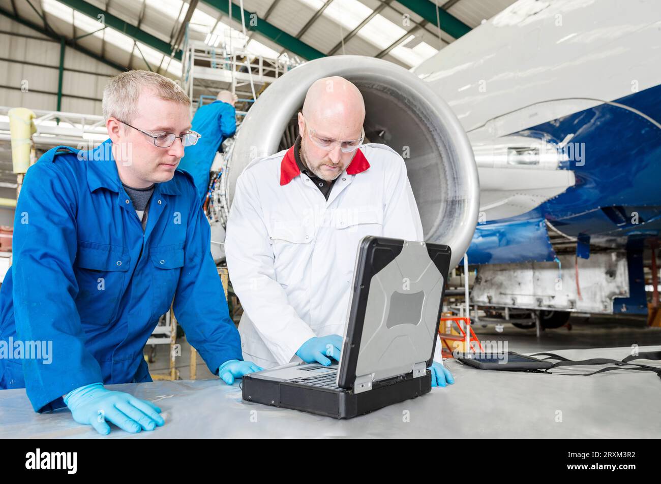 Men using laptop by airplane in hangar Stock Photo