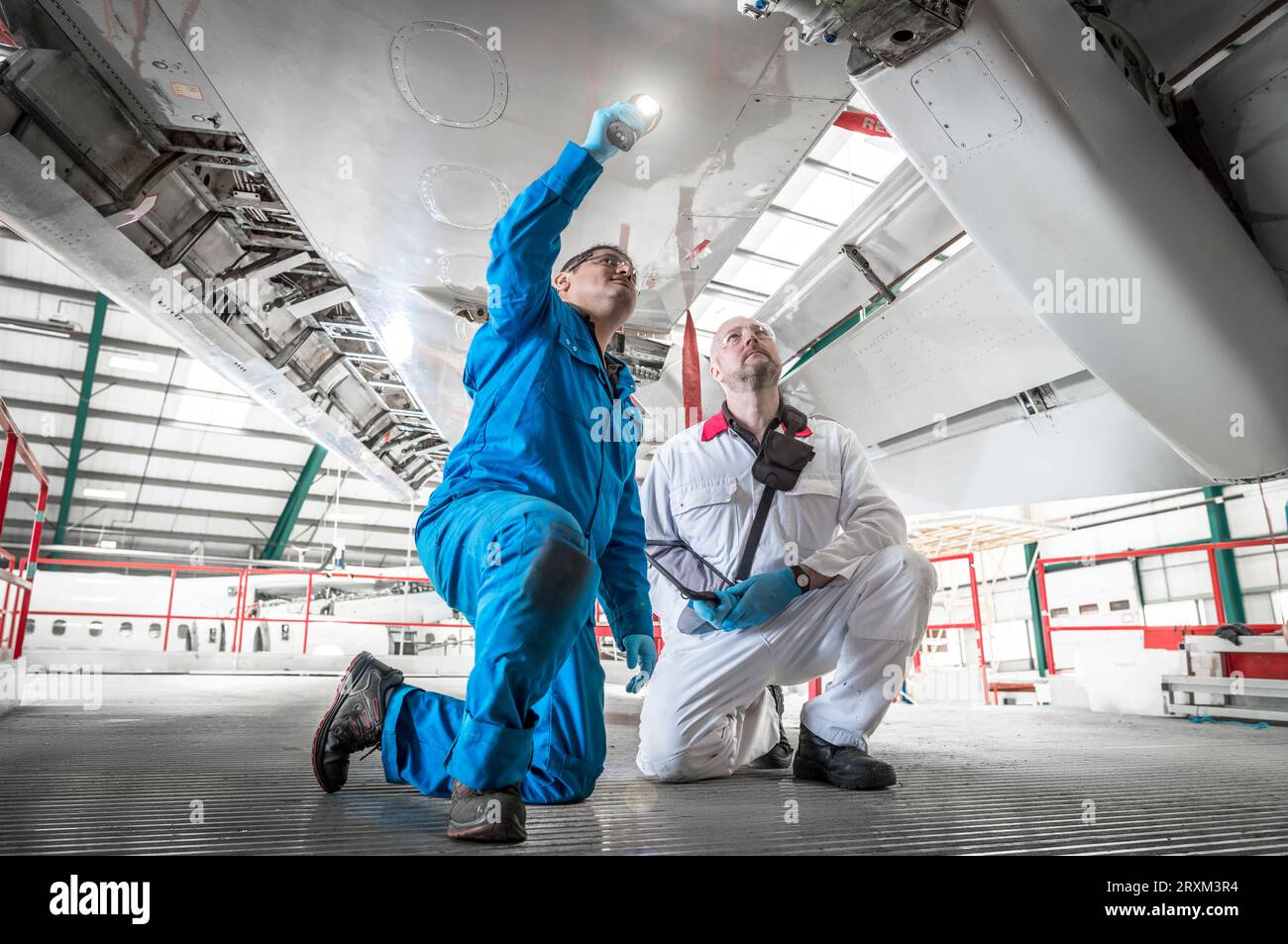 Kneeling men using torch underneath airplane Stock Photo Alamy
