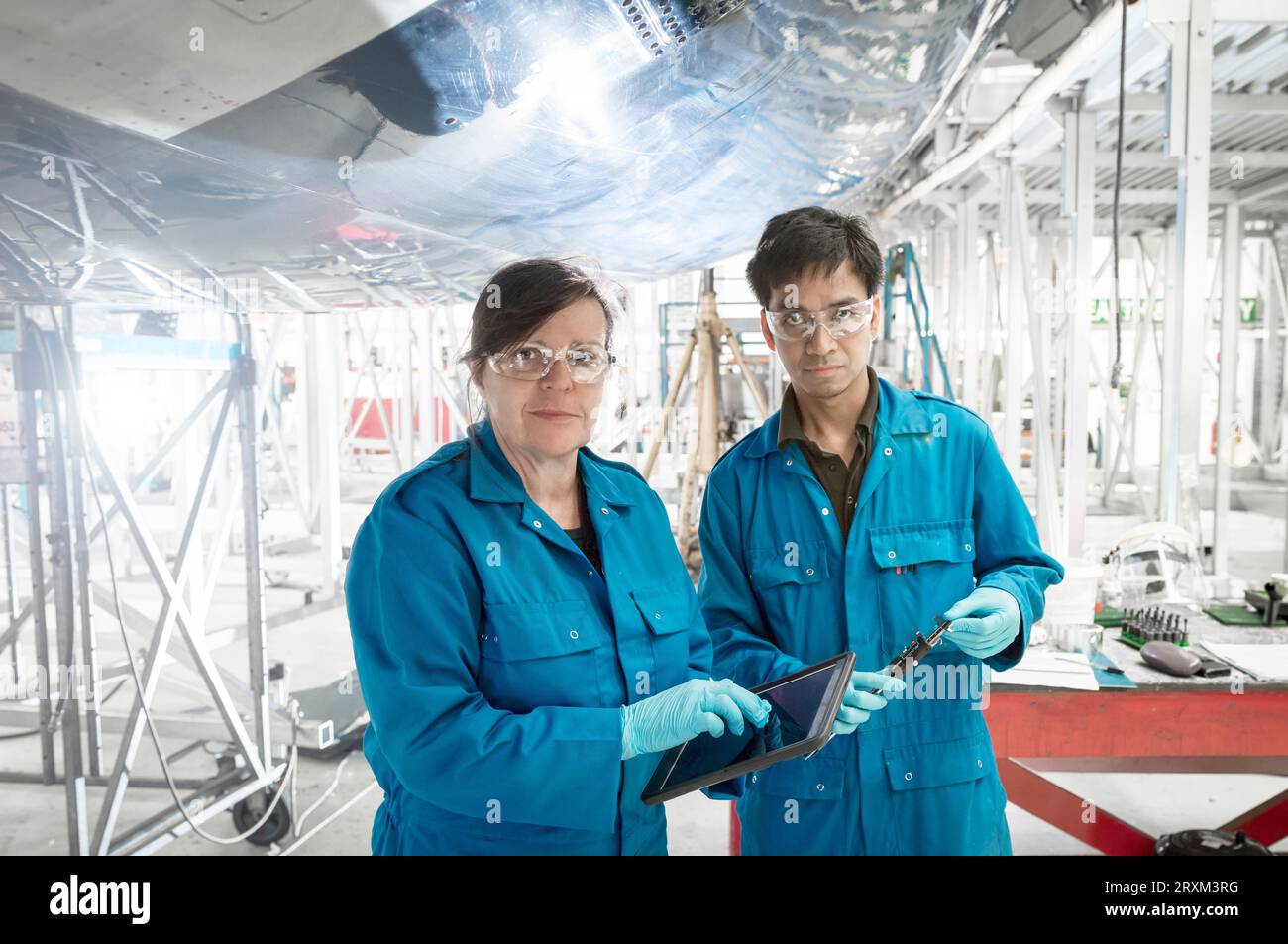 Workers using digital tablet by airplane in hangar Stock Photo