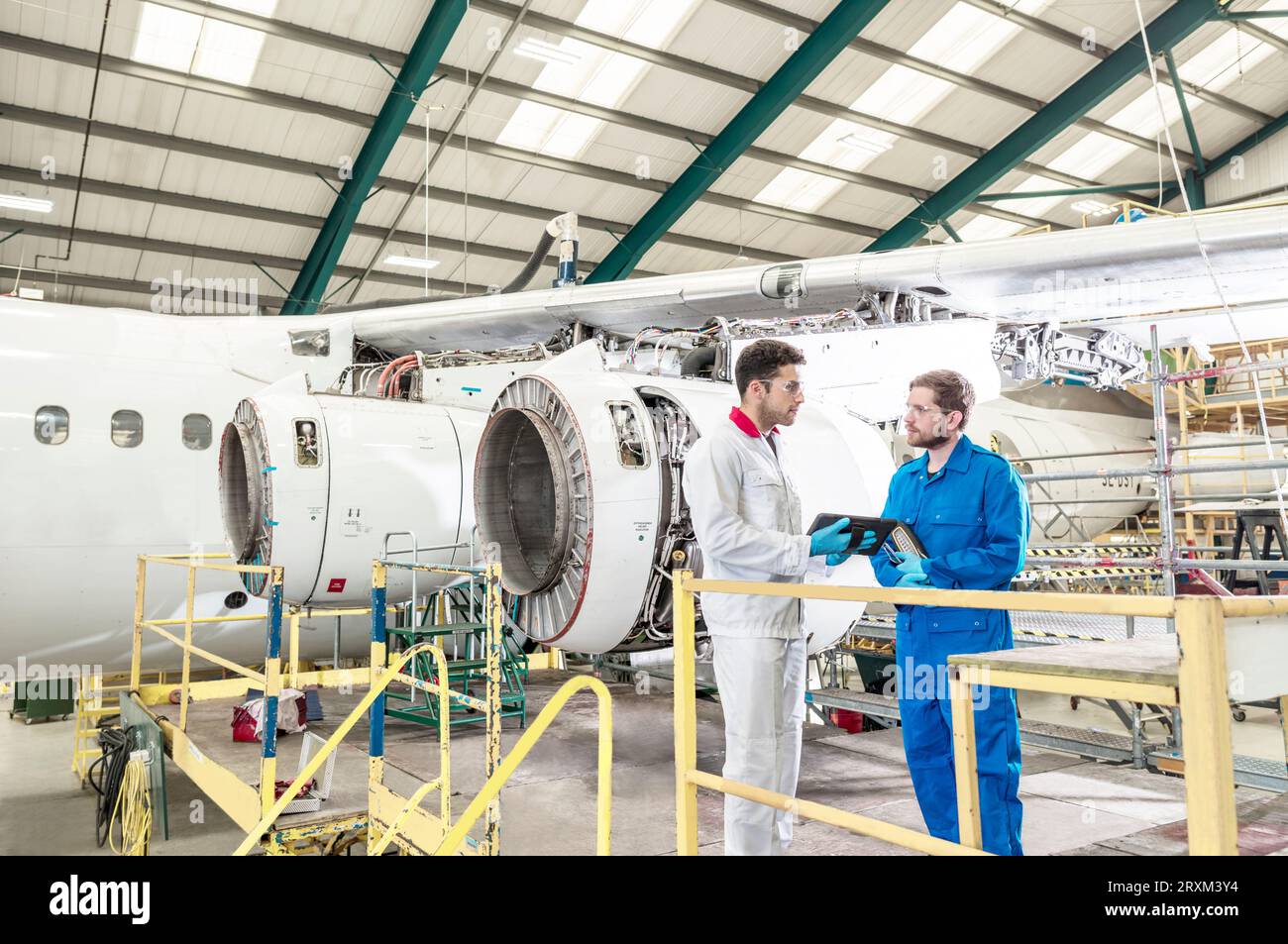 Men using digital tablet in airplane hangar Stock Photo