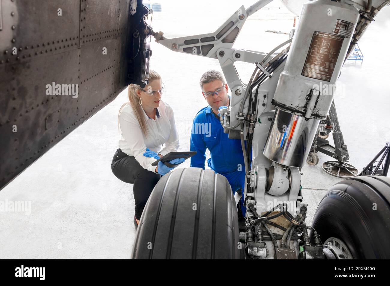 Workers using digital tablet by airplane wheel Stock Photo