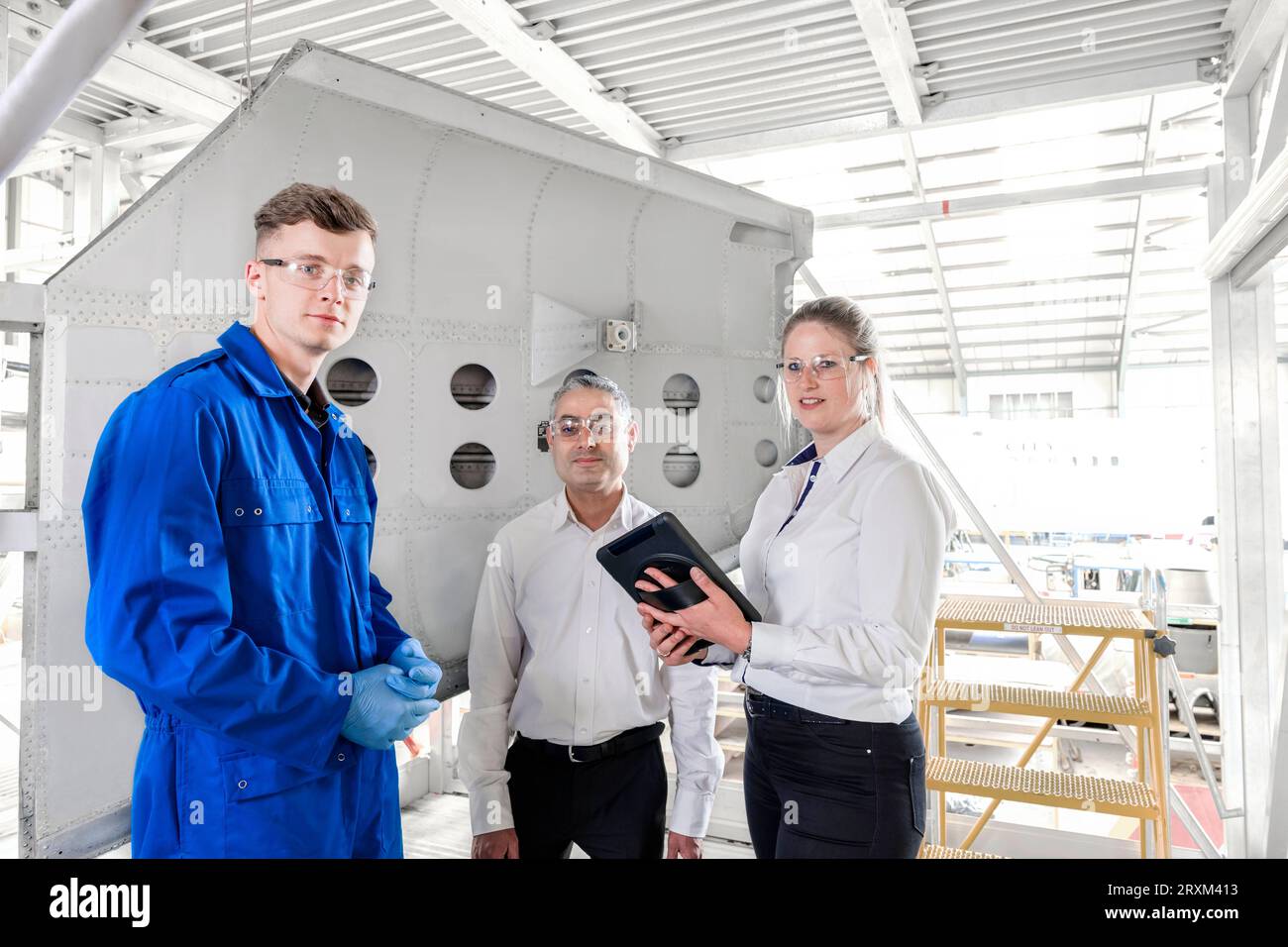 Workers with digital tablet in airplane hangar Stock Photo