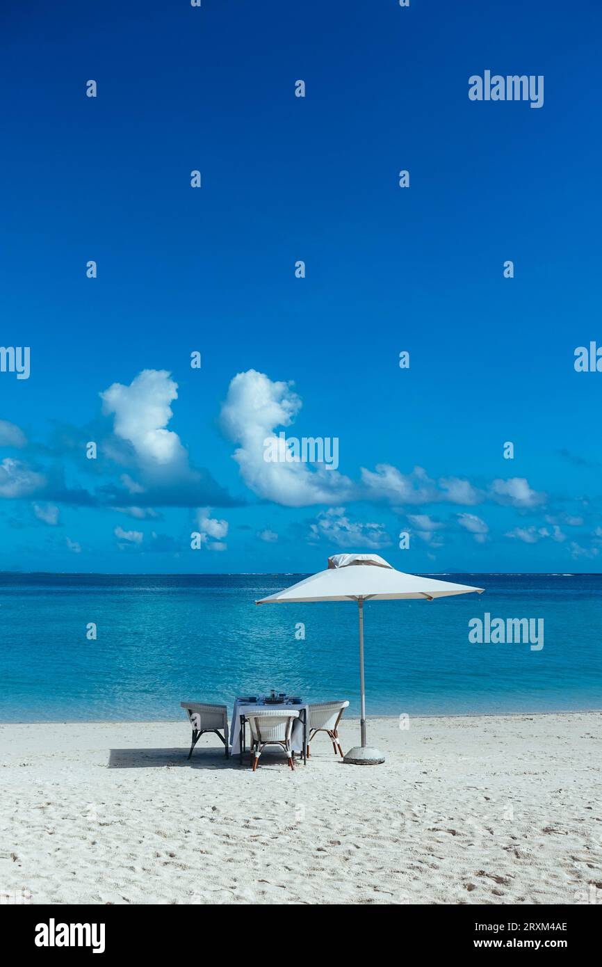Dining table under umbrella on beach Stock Photo - Alamy